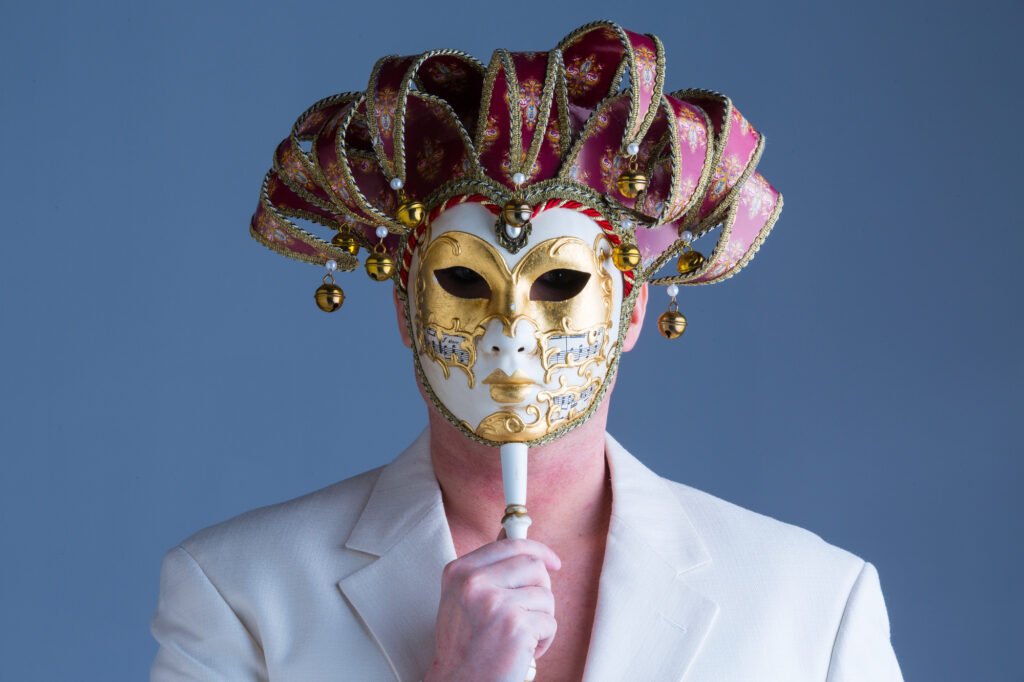 Person in a white jacket wearing an ornate carnival mask