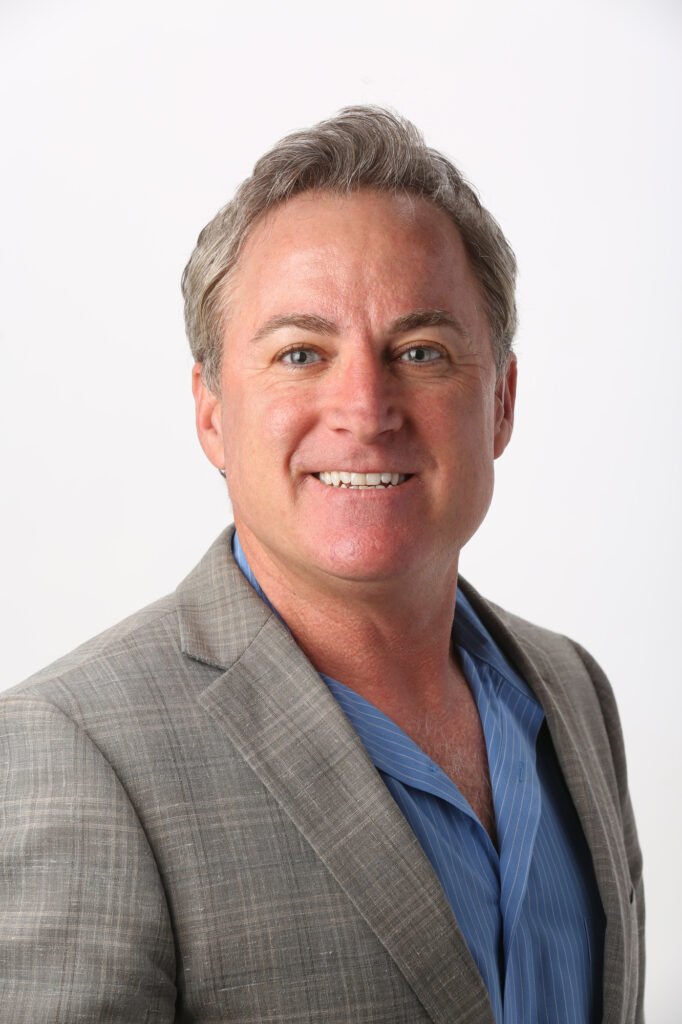 Man in a gray blazer and blue shirt against white