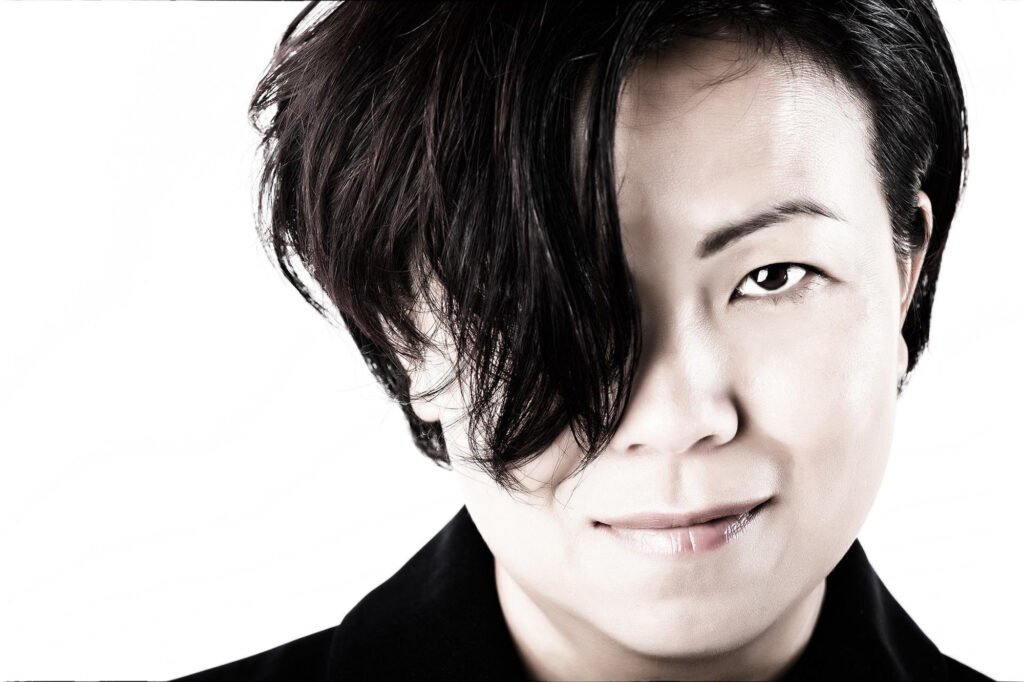 Black-and-white headshot with asymmetrical dark hair
