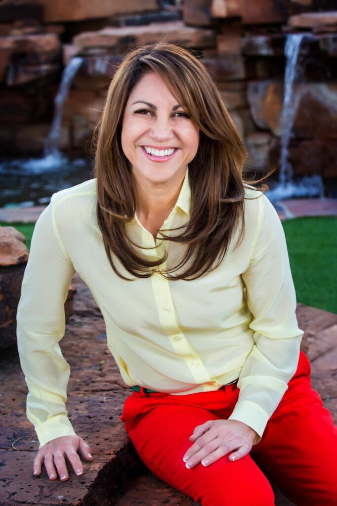 Woman in a pale sweater and red trousers seated outdoors