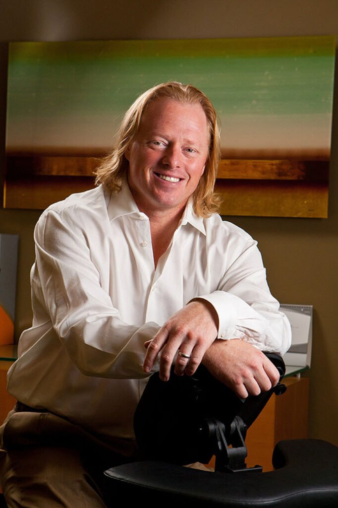 Man in a white shirt seated in a warmly lit interior