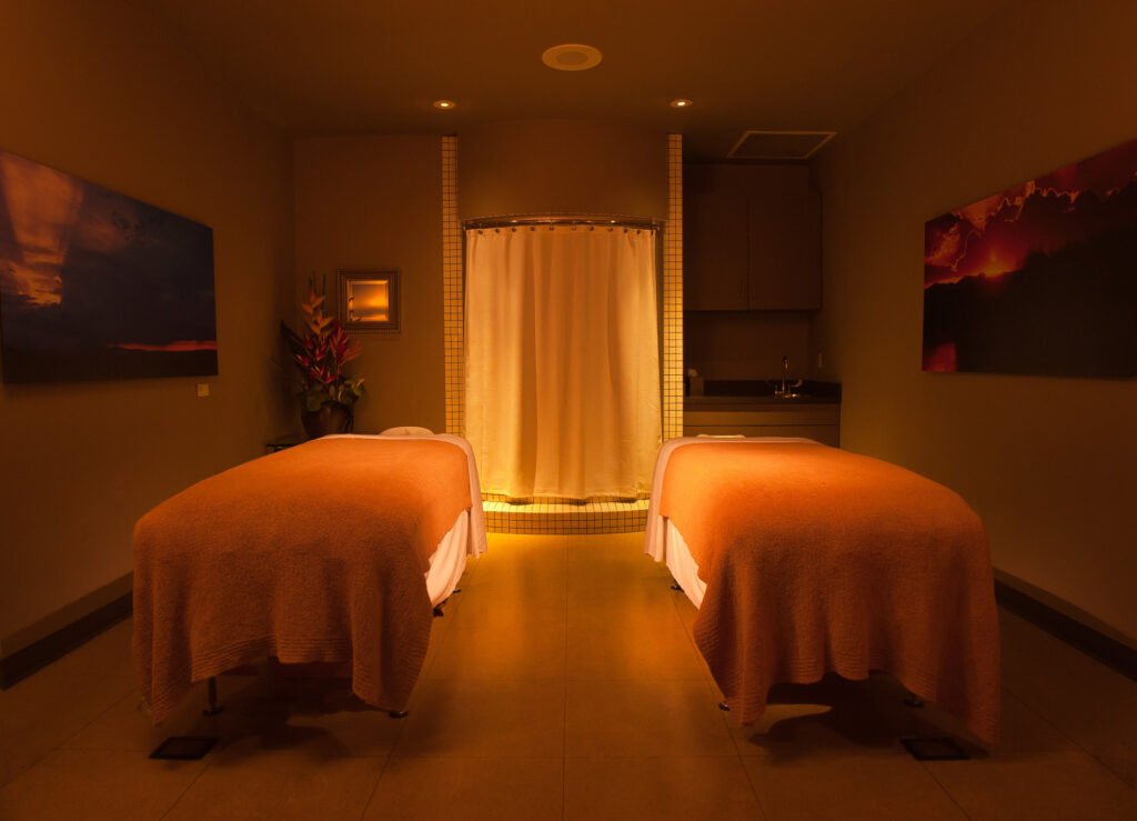 Warmly lit spa treatment room with two massage tables