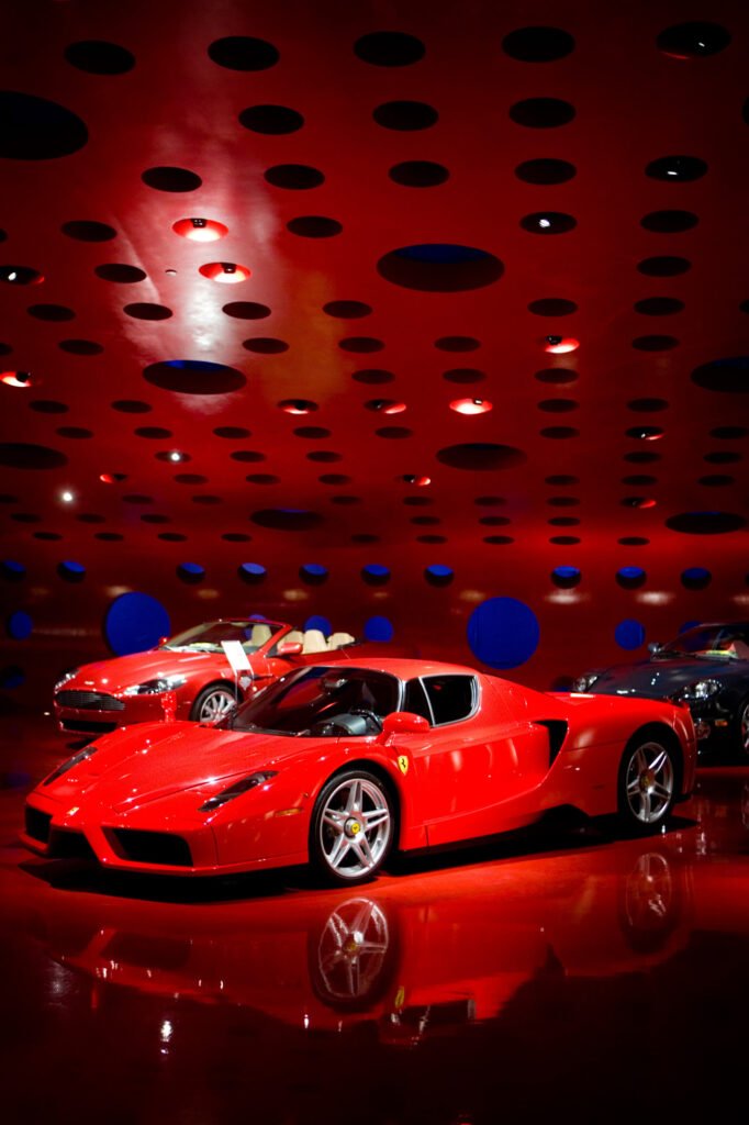 Red sports car beneath a patterned showroom ceiling