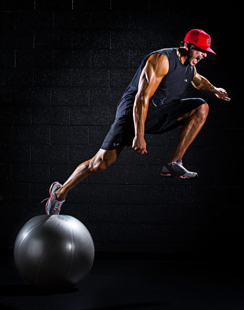 Athlete balancing one foot on an exercise ball against a dark background
