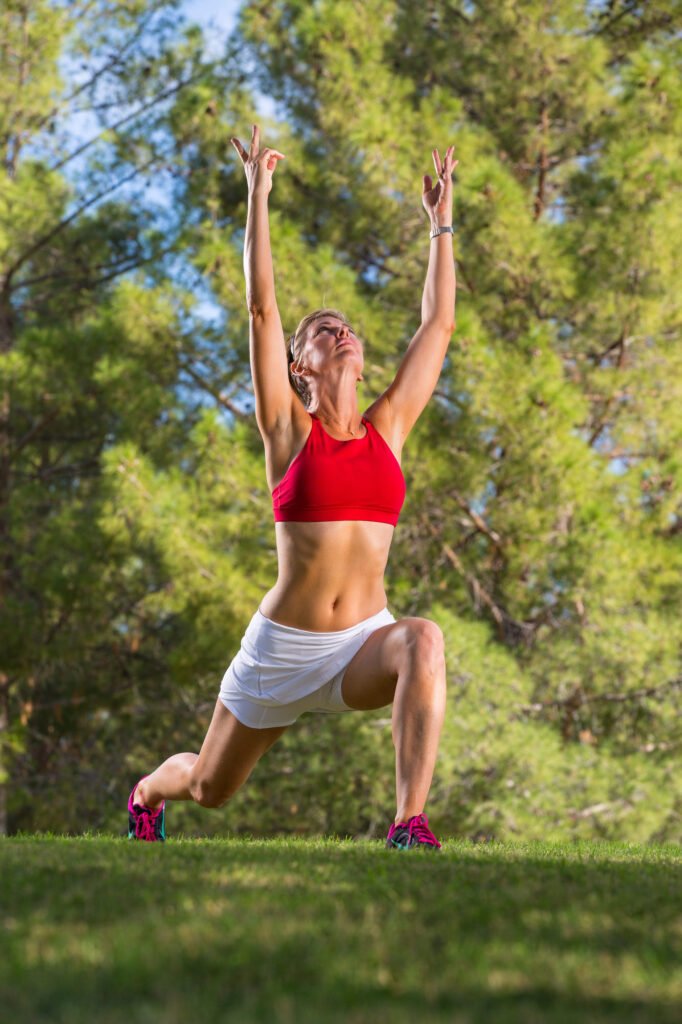 Woman stretching with her arms overhead in a green park