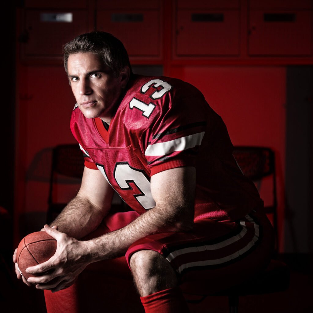 Seated portrait of a football player in a red number 13 uniform