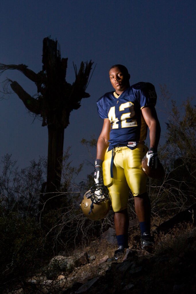 Football player standing among desert plants at dusk