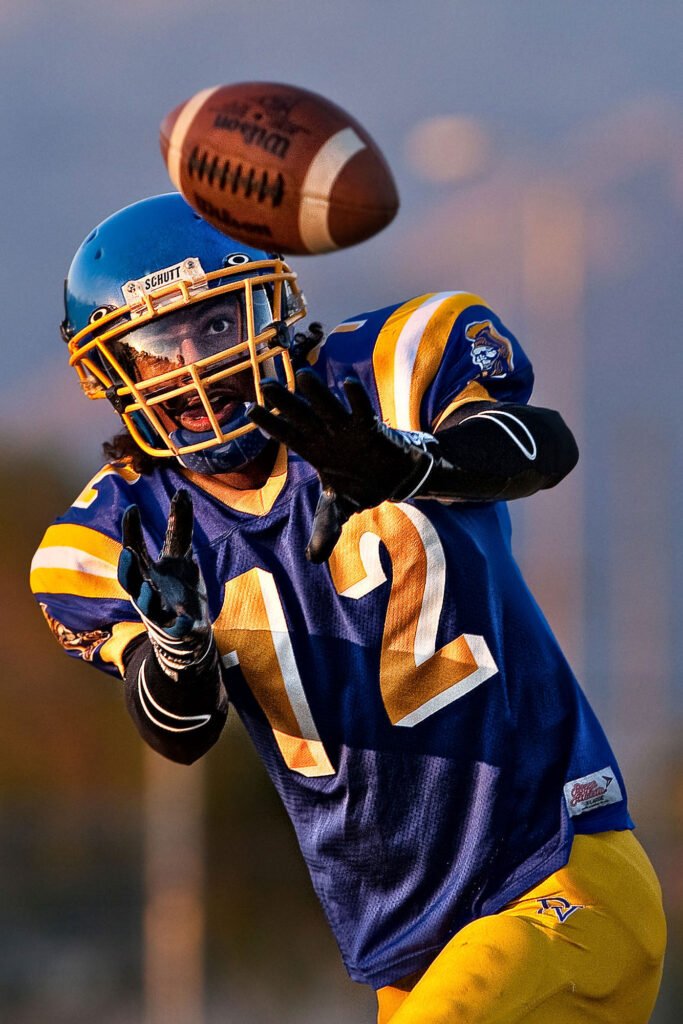 Football player in blue and yellow reaching for a pass