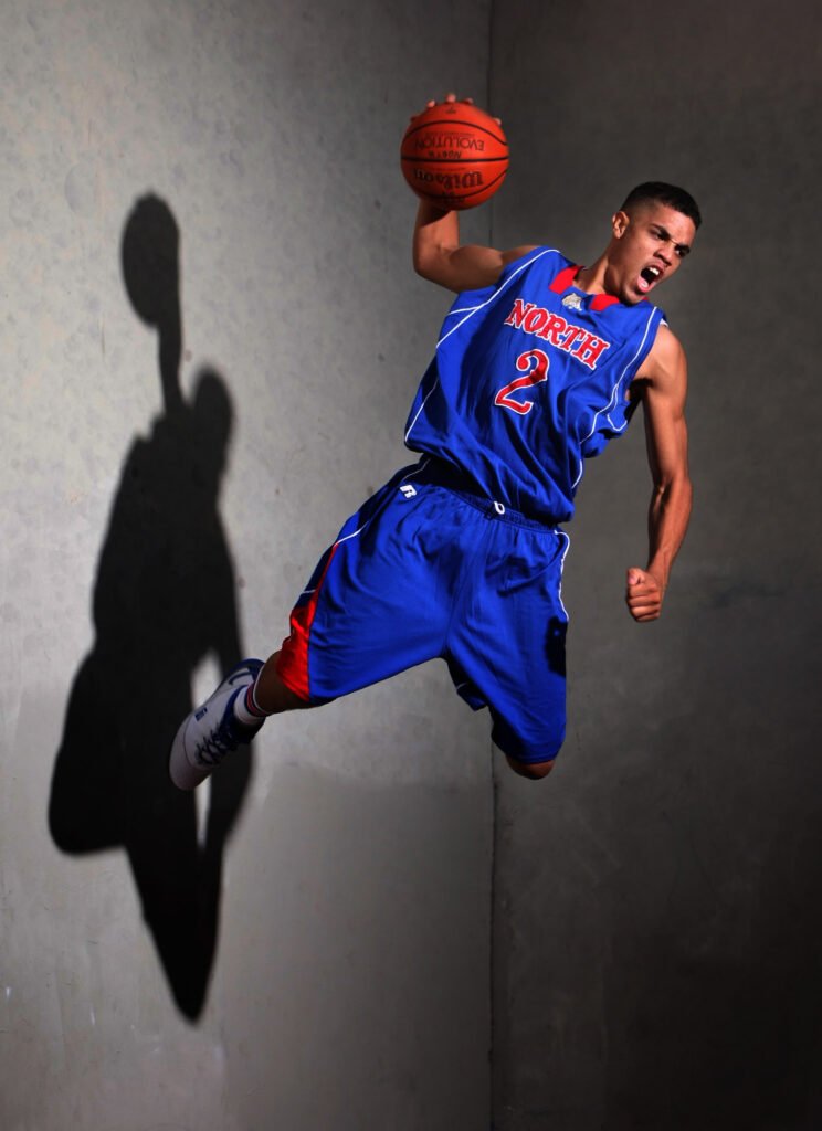 Basketball player in blue jumping beside a wall and shadow
