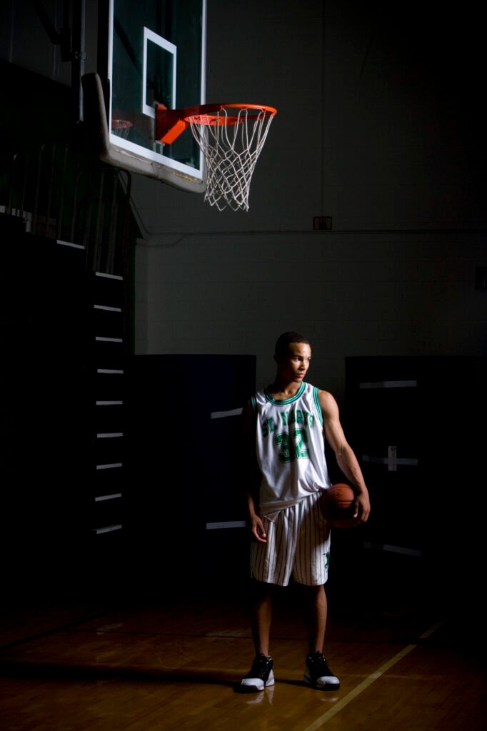 Basketball player standing beneath a hoop in a dark gym