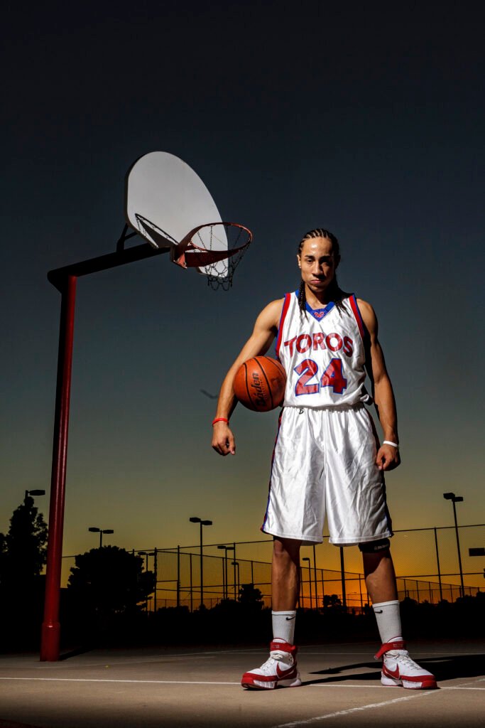 Basketball player standing on an outdoor court at dusk