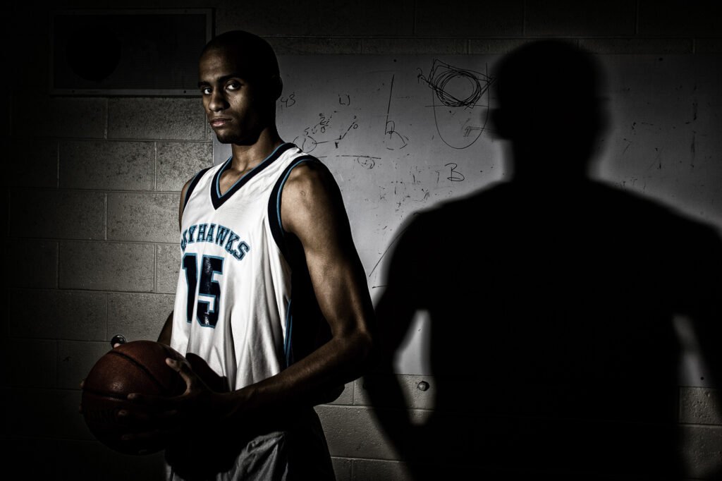 Basketball player holding a ball in dramatic side lighting