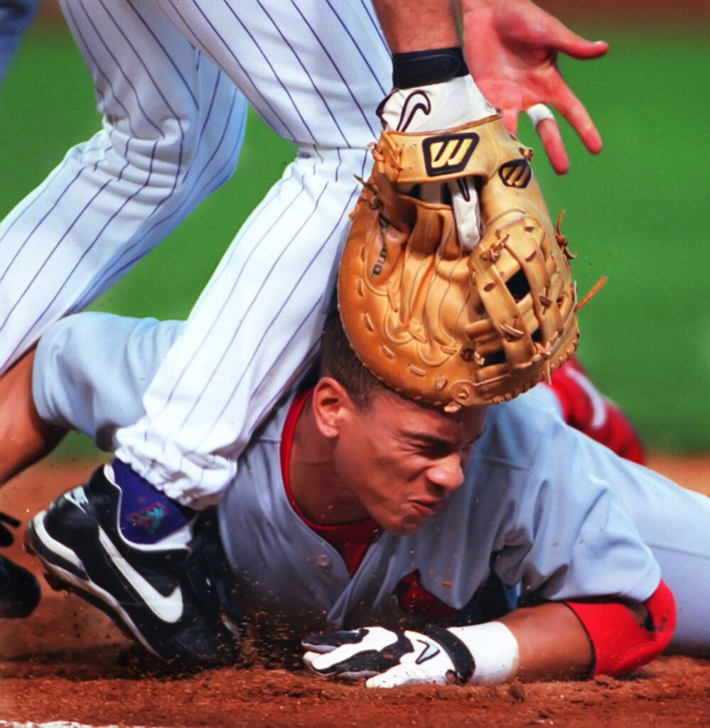 Baseball player sliding beneath an opponent's glove