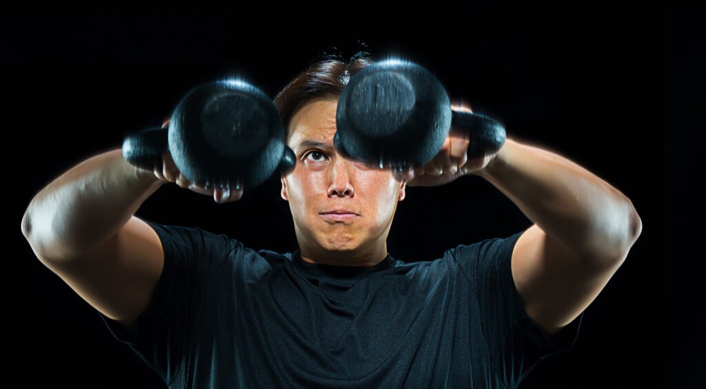 Man holding two dumbbells near his shoulders