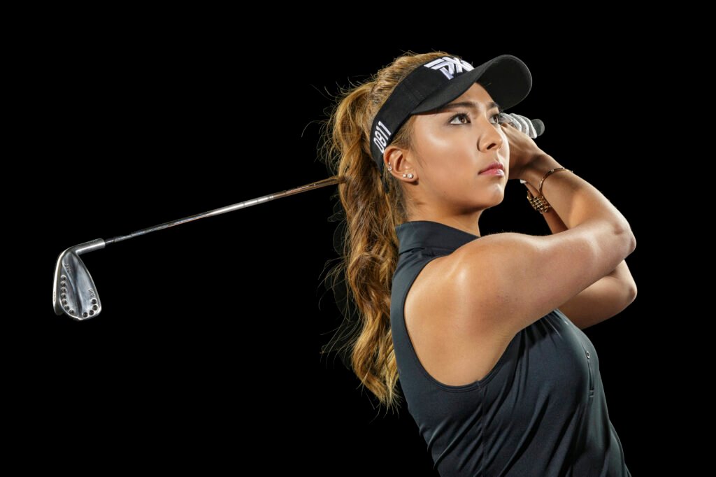 Golfer finishing a swing in a dark sleeveless top
