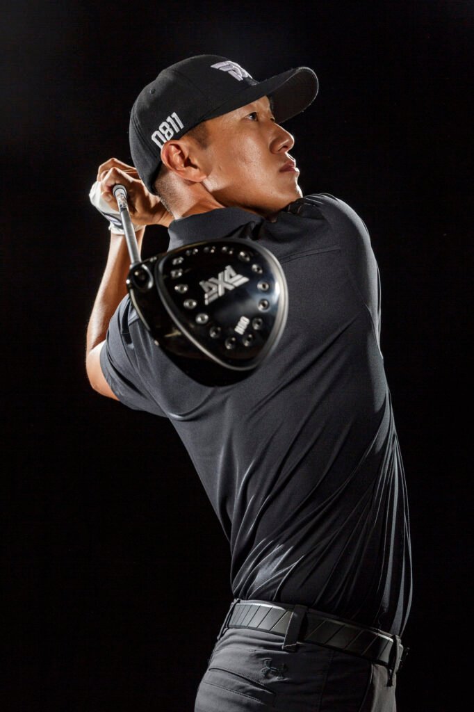 Golfer in a dark cap and shirt at the end of a swing