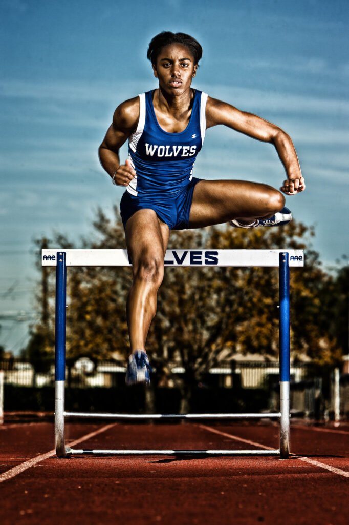 Track athlete clearing a hurdle on a running track